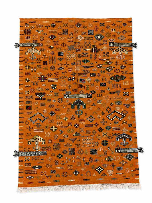 Tapis Akhnif orange rouille à symboles berbères, bandes sumak et pompons d'angle, poils ras, vue de dessus