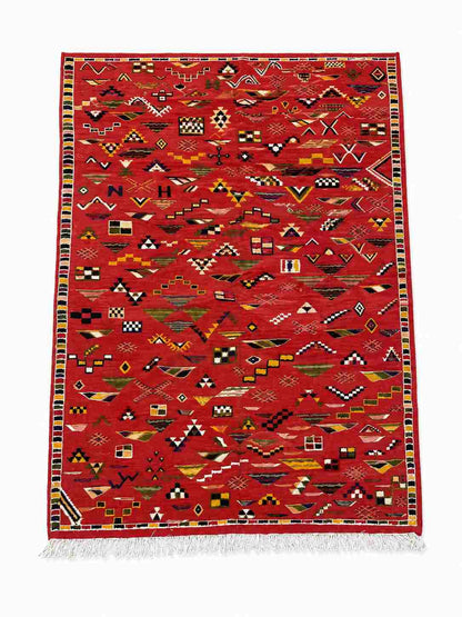 Tapis Akhnif rouge à champ de symboles berbères et bordure damier, poils ras, vue de dessus